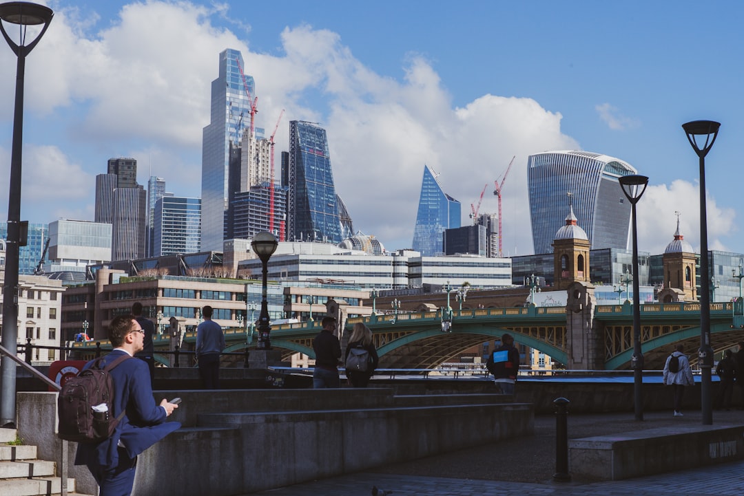 A woman standing on a bridge looking at her cell phone