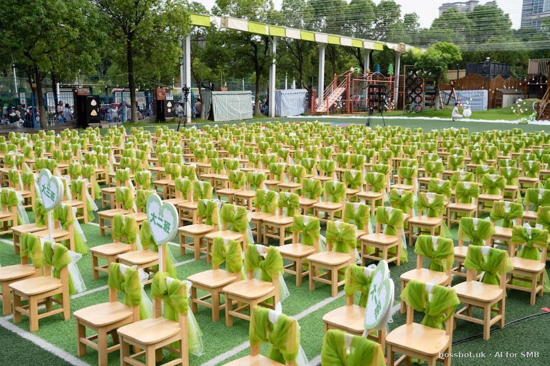 Many small wooden chairs with green sashes on artificial turf.