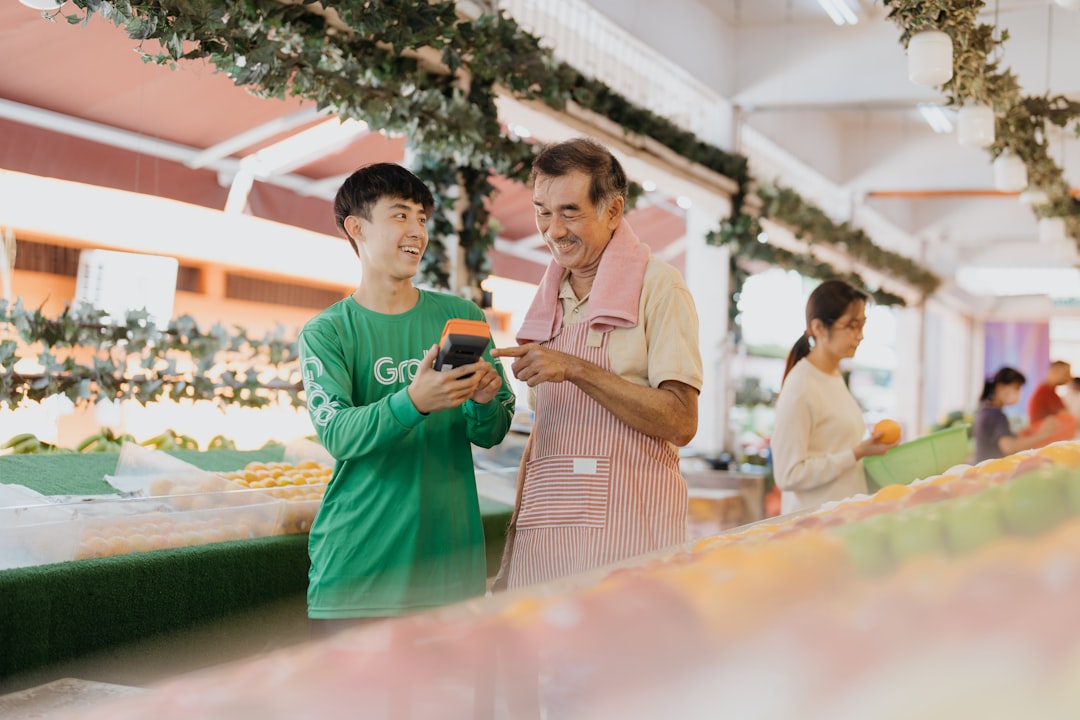Two men standing next to each other looking at a cell phone