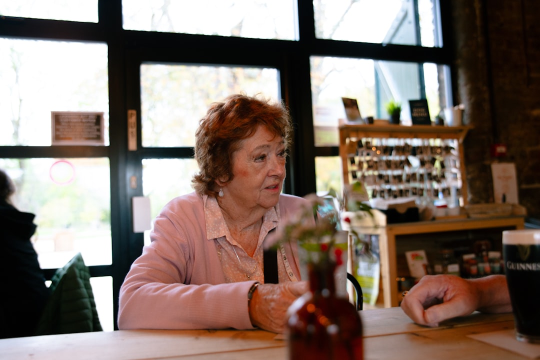 Elderly woman with red hair at a table.
