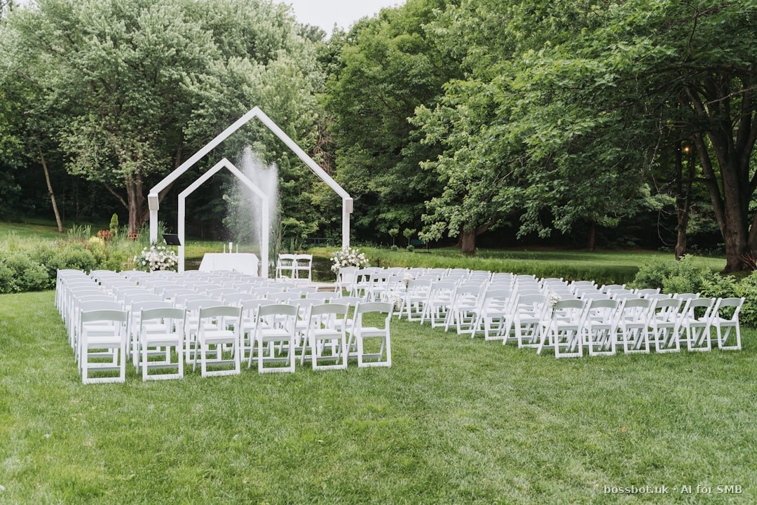 Outdoor wedding ceremony setup with white chairs and arch.