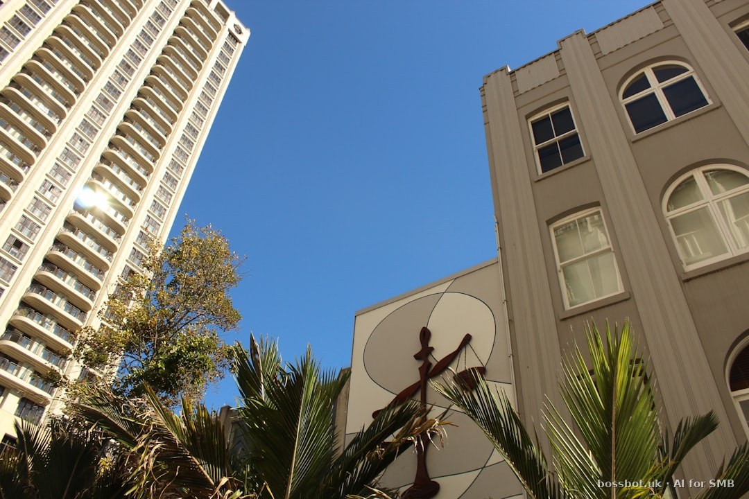 Tall buildings and palm trees against a clear blue sky.