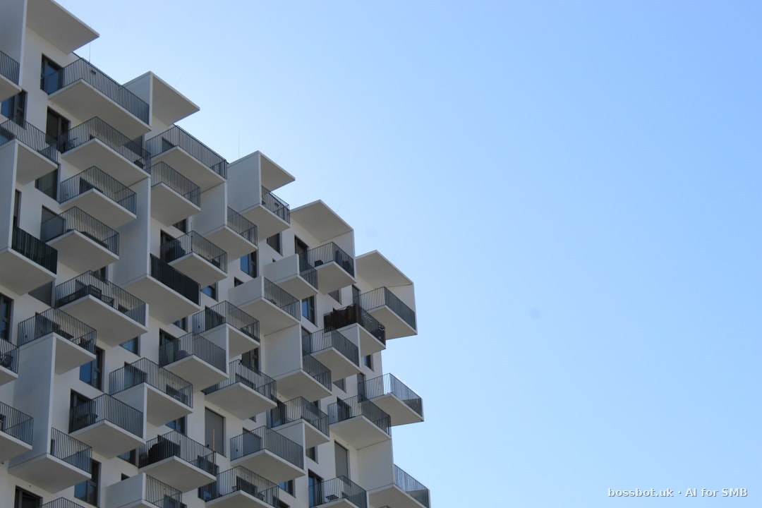 Modern white building with many balconies against a blue sky.