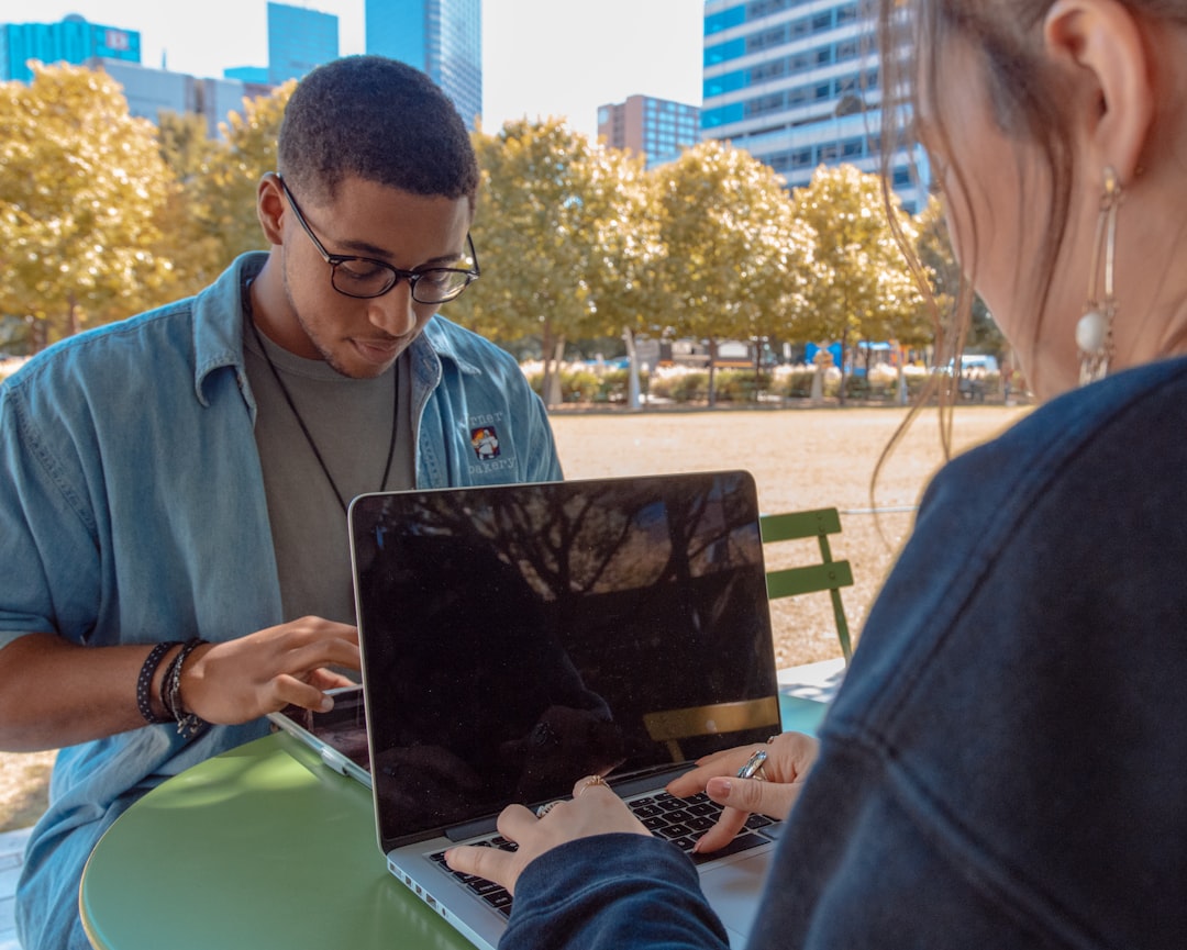 Man and woman sitting while using macbook pro
